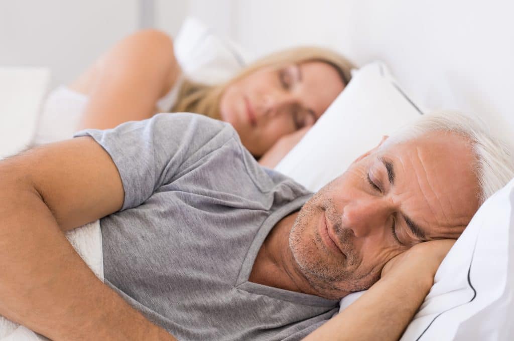 Senior man and woman sleeping. Senior man and woman resting with eyes closed. Mature couple sleeping together in their bed.