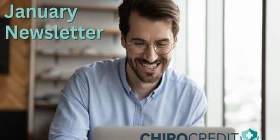 Male professional with brown hair, brown facial hair, and glasses smiling at his laptop.