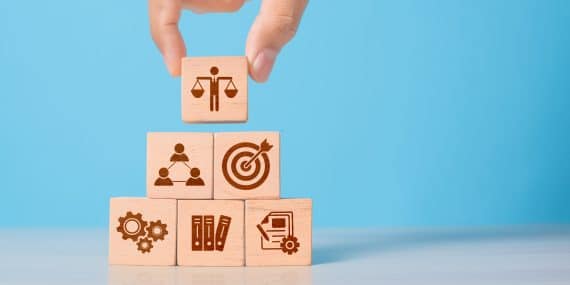 Wooden cube with ethics symbol held in hand.