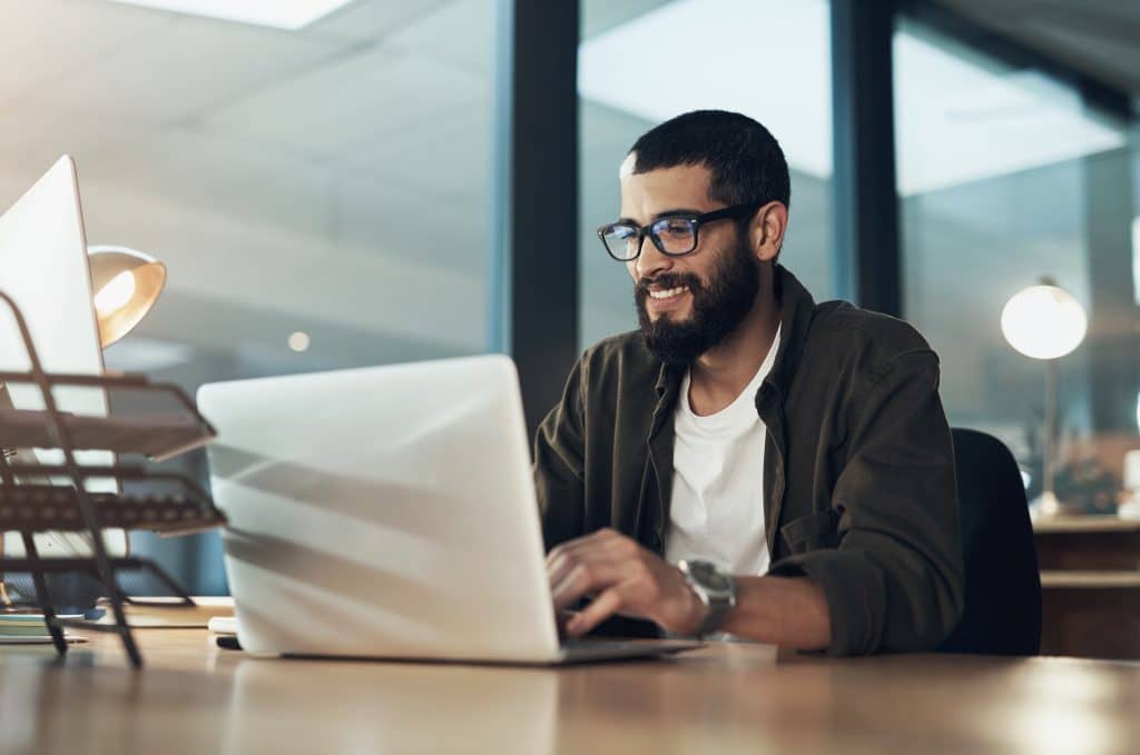 Smiling professional looking at an open laptop.